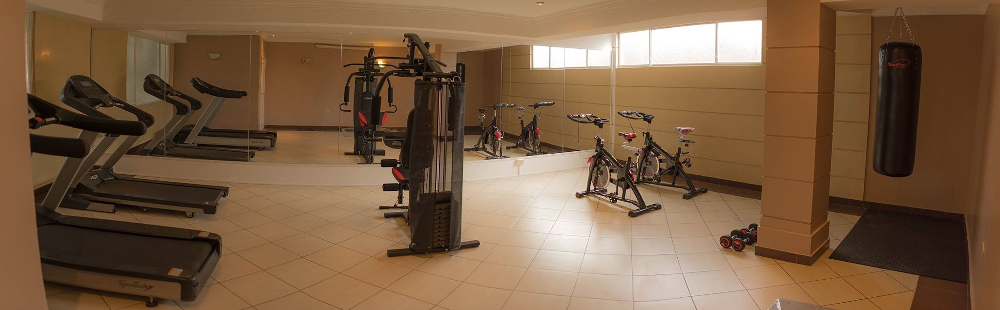Un gimnasio con cintas de correr, elípticas y bicicletas estáticas.