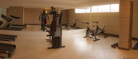 Un gimnasio con cintas de correr, elípticas y bicicletas estáticas.