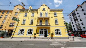 A yellow building with a prominent entrance, multiple windows, and a balcony. - Hotel Lehenerhof Salzburg (Salzburg)
