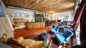 A spacious living area with a wooden ceiling, a bar area, and seating arrangements including a sofa and armchairs. - Hotel Lehenerhof Salzburg (Salzburg)