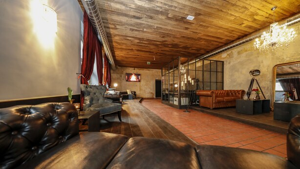 A spacious room with a wooden ceiling, leather sofas, a fireplace, and a large mirror. - Hotel Lehenerhof Salzburg (Salzburg)