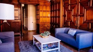 A living room with a blue sofa, a white coffee table with magazines, and a wooden wall panel. - Zentric Hostel (León)
