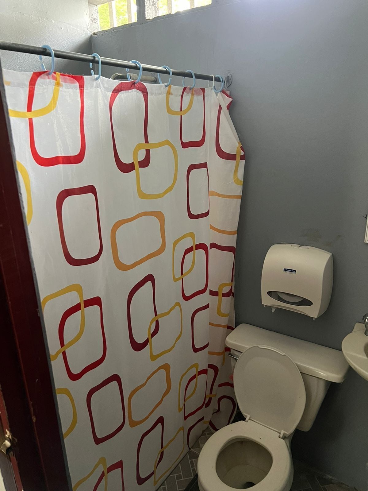 A bathroom with a toilet, a sink, and a paper towel dispenser.