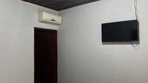 A room with a closed door, a mounted air conditioner, and a flat-screen TV on the wall. - Hotel Guanacaste (Liberia)