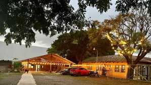 A rustic building with a covered outdoor area, a gravel path, and a parked car. - Hotel Guanacaste (Liberia)
