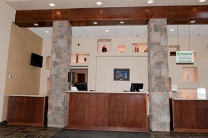 A reception area with a stone pillar, a wooden reception desk, a flat-screen TV, and a sign for National Bank.