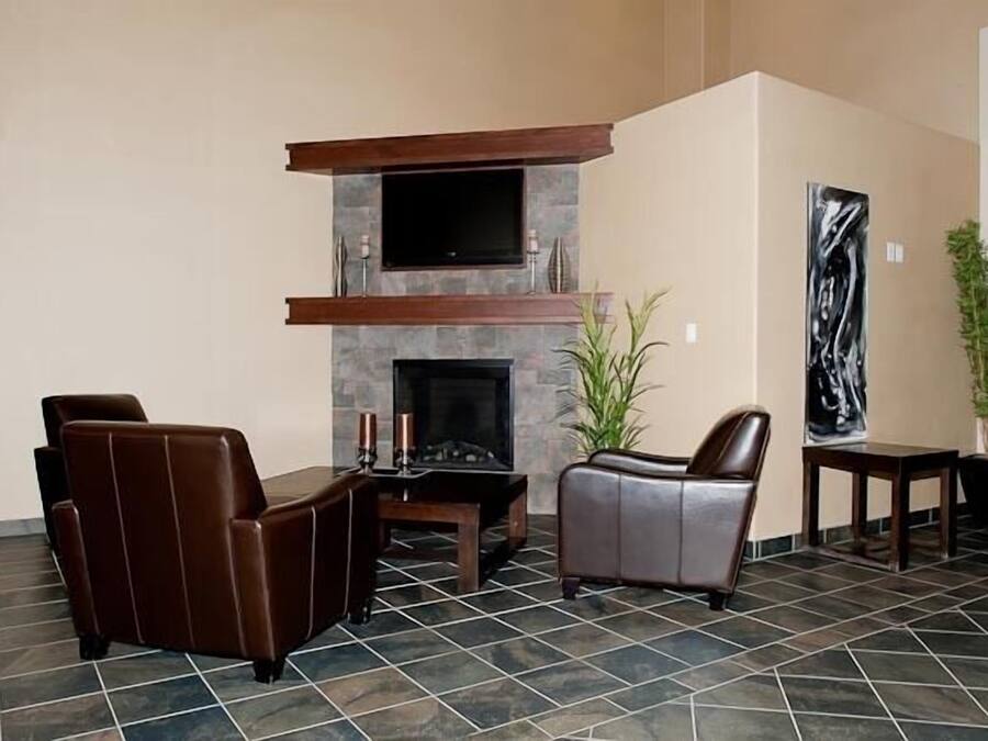 Una sala de estar con chimenea, sillones de cuero, un televisor de pantalla plana y un cuadro abstracto grande.