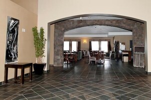 A spacious lobby with a high ceiling, stone archway, and a large painting on the left.