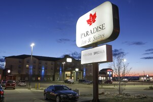 A hotel sign with a maple leaf logo and the name "Paradise Inn & Suites".