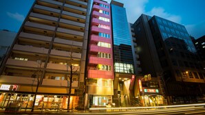 A multi-story building with a mix of residential and commercial spaces, including a brightly lit restaurant at street level. - Senba Hostel (Osaka)