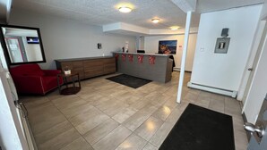 Ett väntrum med en reception i trä, en röd soffa, ett litet bord och en svart matta.