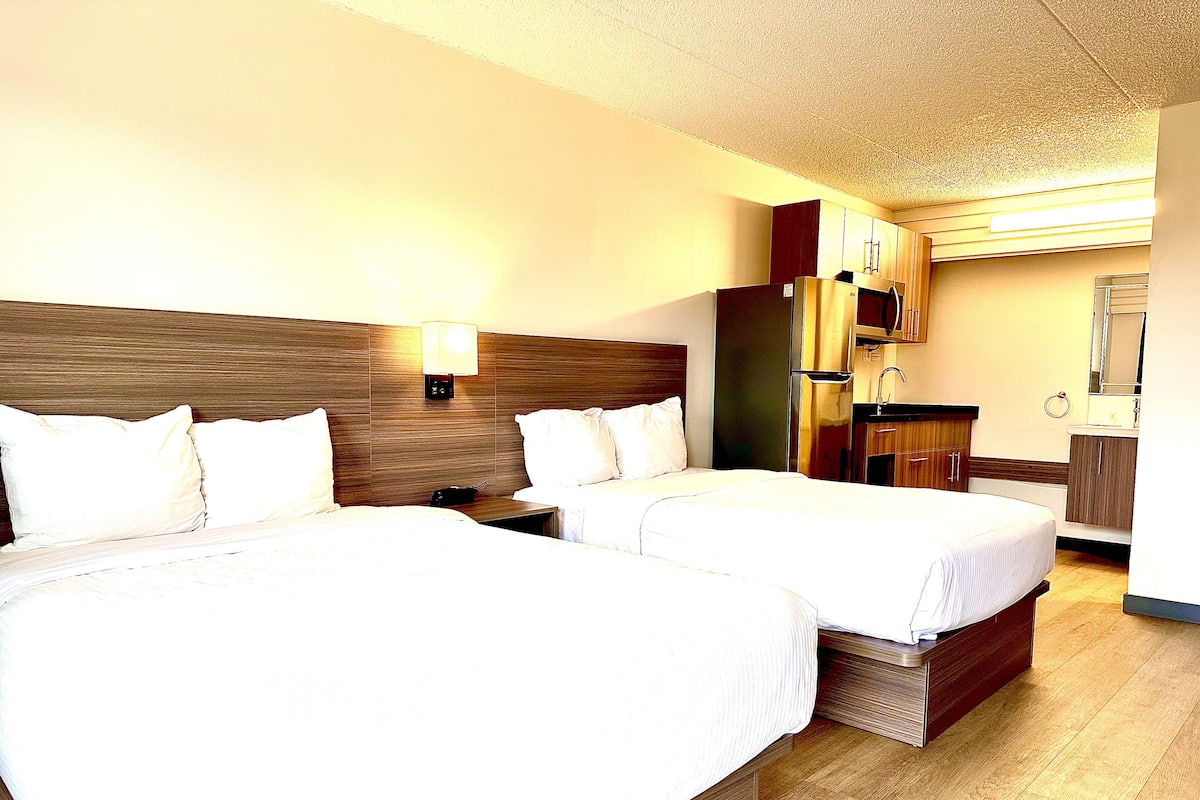 Een hotelkamer met twee bedden, een kitchenette en een badkamer.