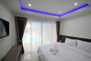 A hotel room with a bed, a flat-screen TV mounted on the wall, and a window with sheer curtains. - Lanta Fevrier Resort (Ko Lanta)