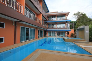 A multi-story hotel with a swimming pool, balconies, and large windows. - Lanta Fevrier Resort (Ko Lanta)