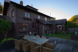 Enjoy the serene atmosphere of this charming home, featuring a spacious deck with wicker furniture and a beautiful garden.