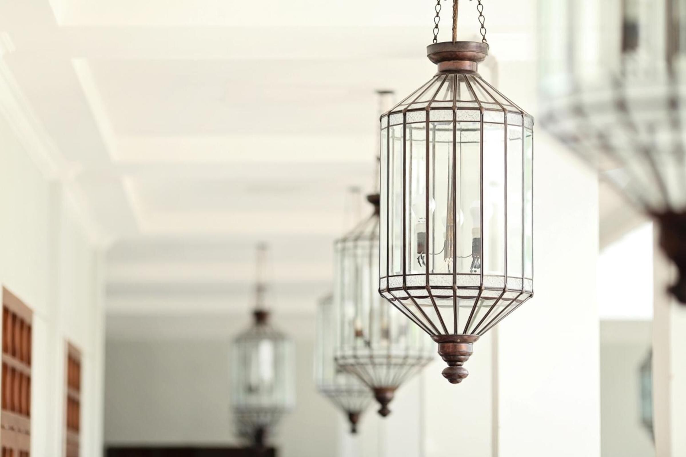 Une série de lanternes métalliques suspendues, au design classique, qui sont fixées au plafond d’un couloir bien éclairé.