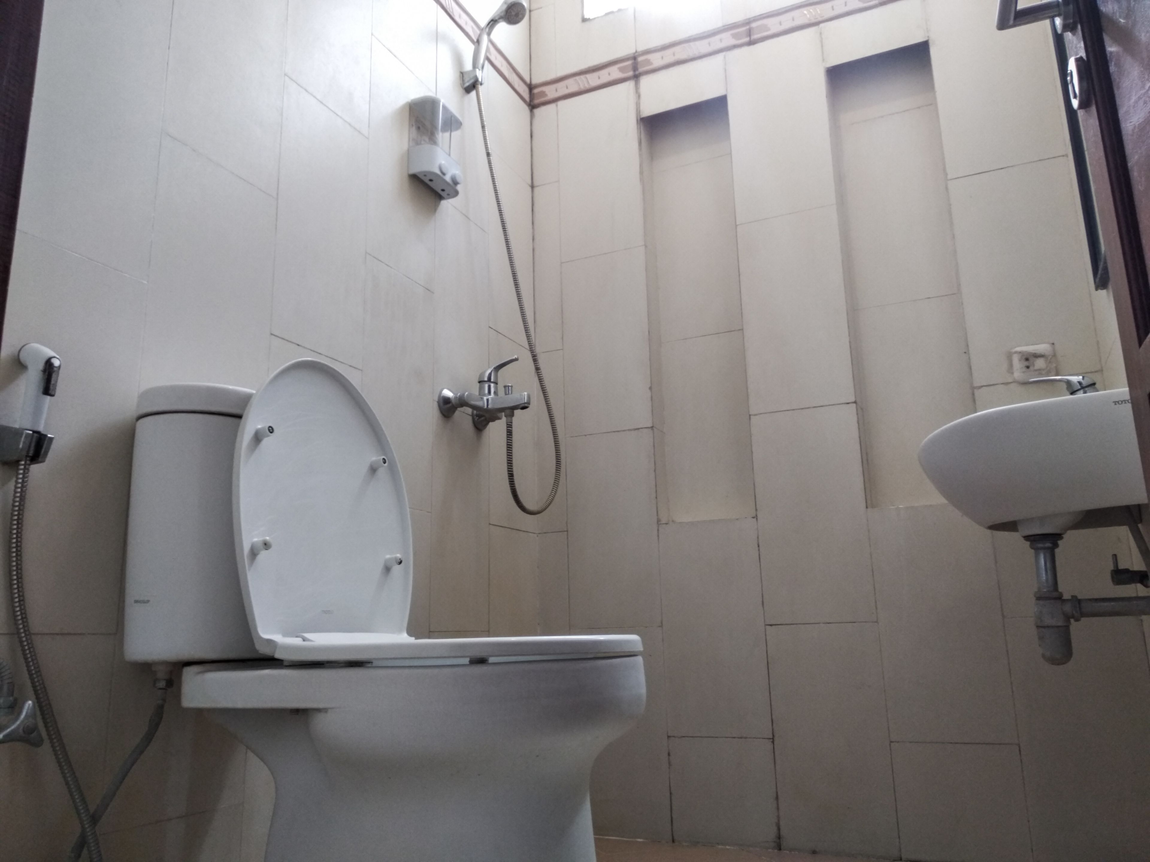 A bathroom with a toilet, a shower, and a sink.