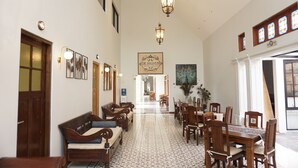 A spacious hallway with a dining area, wooden furniture, and decorative lighting fixtures. - De Halimun Guest House (Bandung)