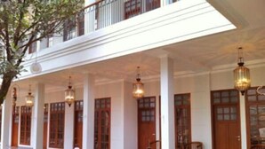 A covered outdoor area with wooden tables and benches, traditional doors, and hanging lanterns. - De Halimun Guest House (Bandung)