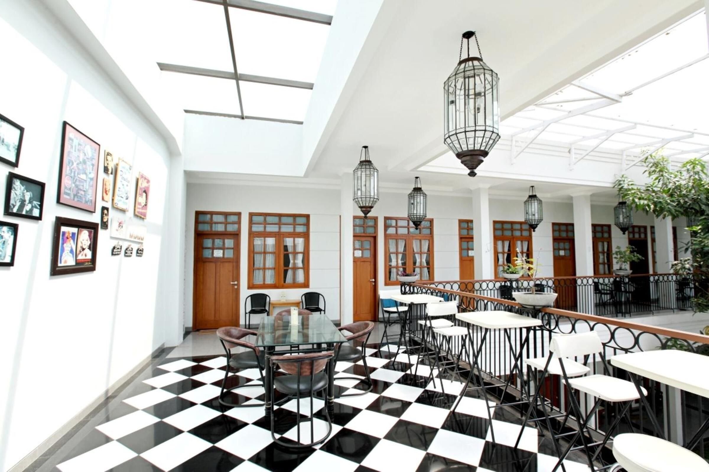A spacious indoor area with a checkered floor, multiple tables and chairs, hanging lanterns, and framed pictures on the walls.