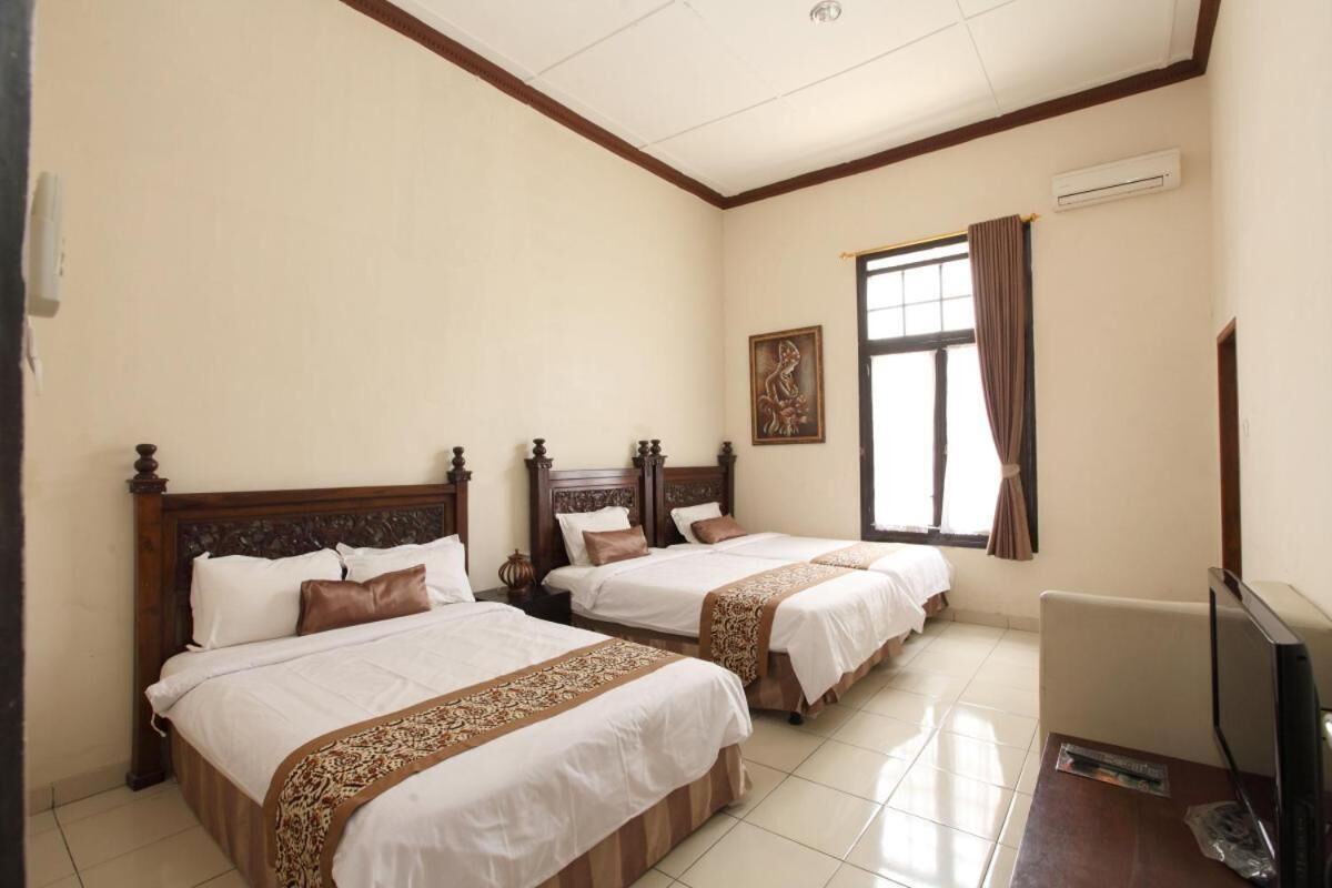 A hotel room with two beds, a television, and a window with curtains.