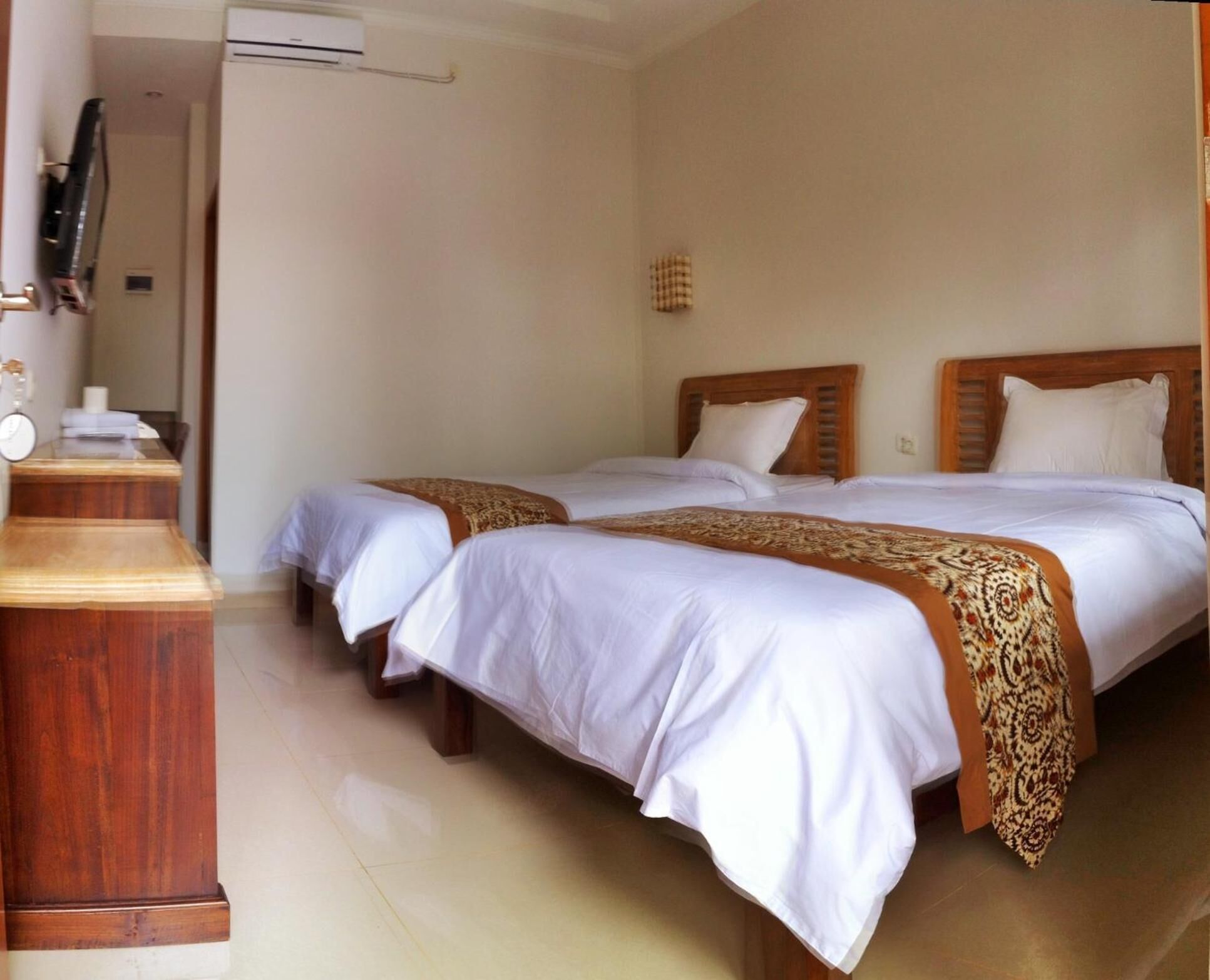 Habitación de hotel con dos camas, un aparador de madera, un televisor de pantalla plana y un calefactor pequeño de pared.