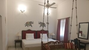 Un dormitorio con cama, una silla colgante, un escritorio y un espejo.