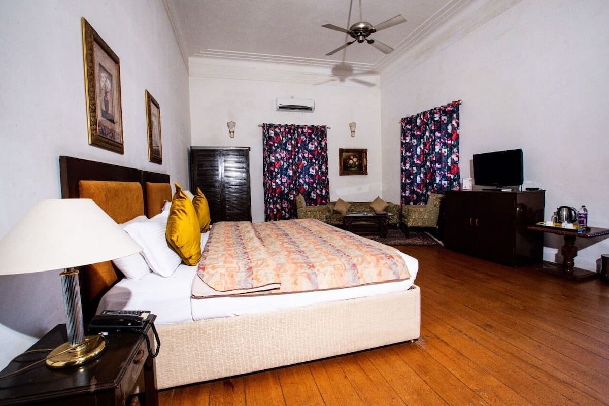 A hotel room with a bed, a desk, a television, and a ceiling fan.