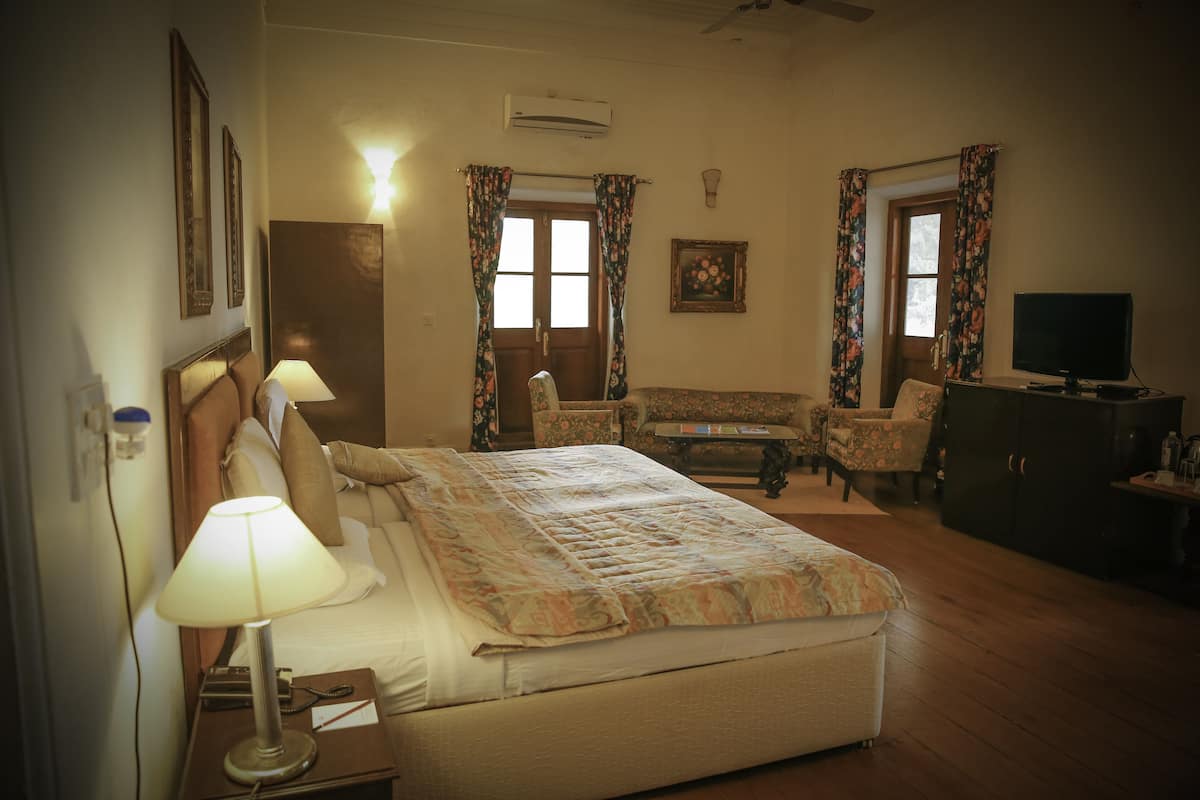 A hotel room with a bed, bedside lamps, a desk, a chair, a television, and a wardrobe.