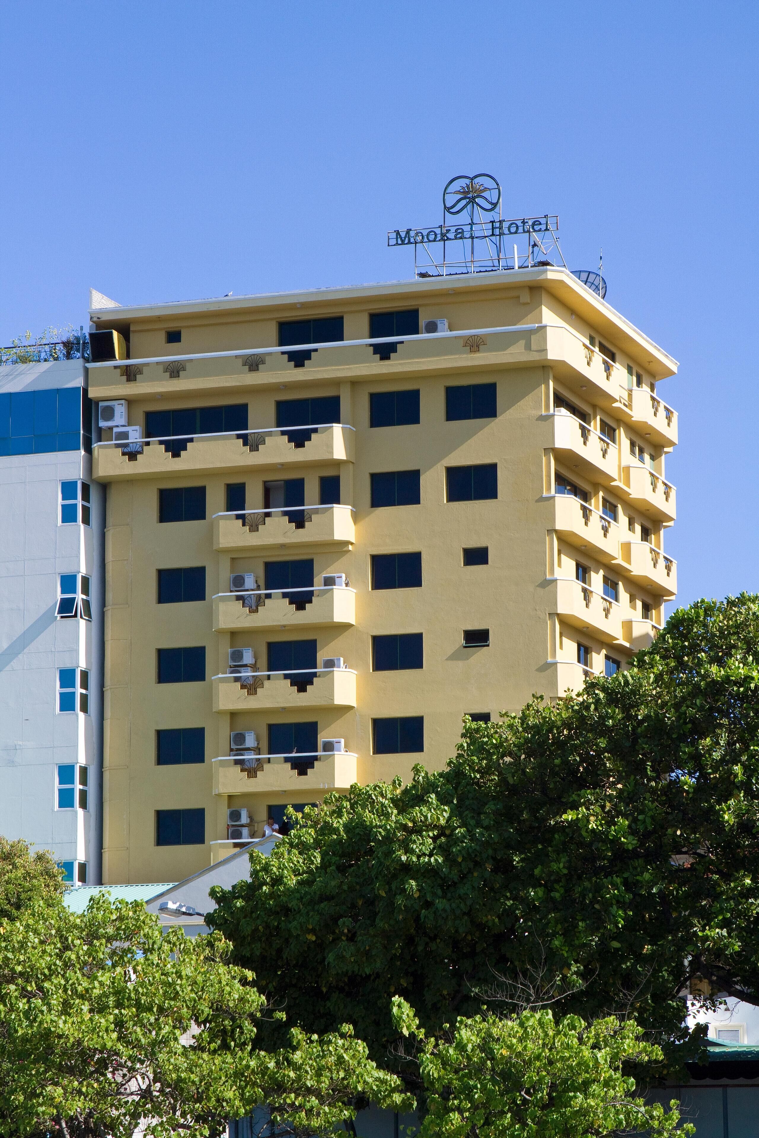 Un hotel de varios pisos con balcones, unidades de aire acondicionado y un cartel que dice "Mooka Hotel".