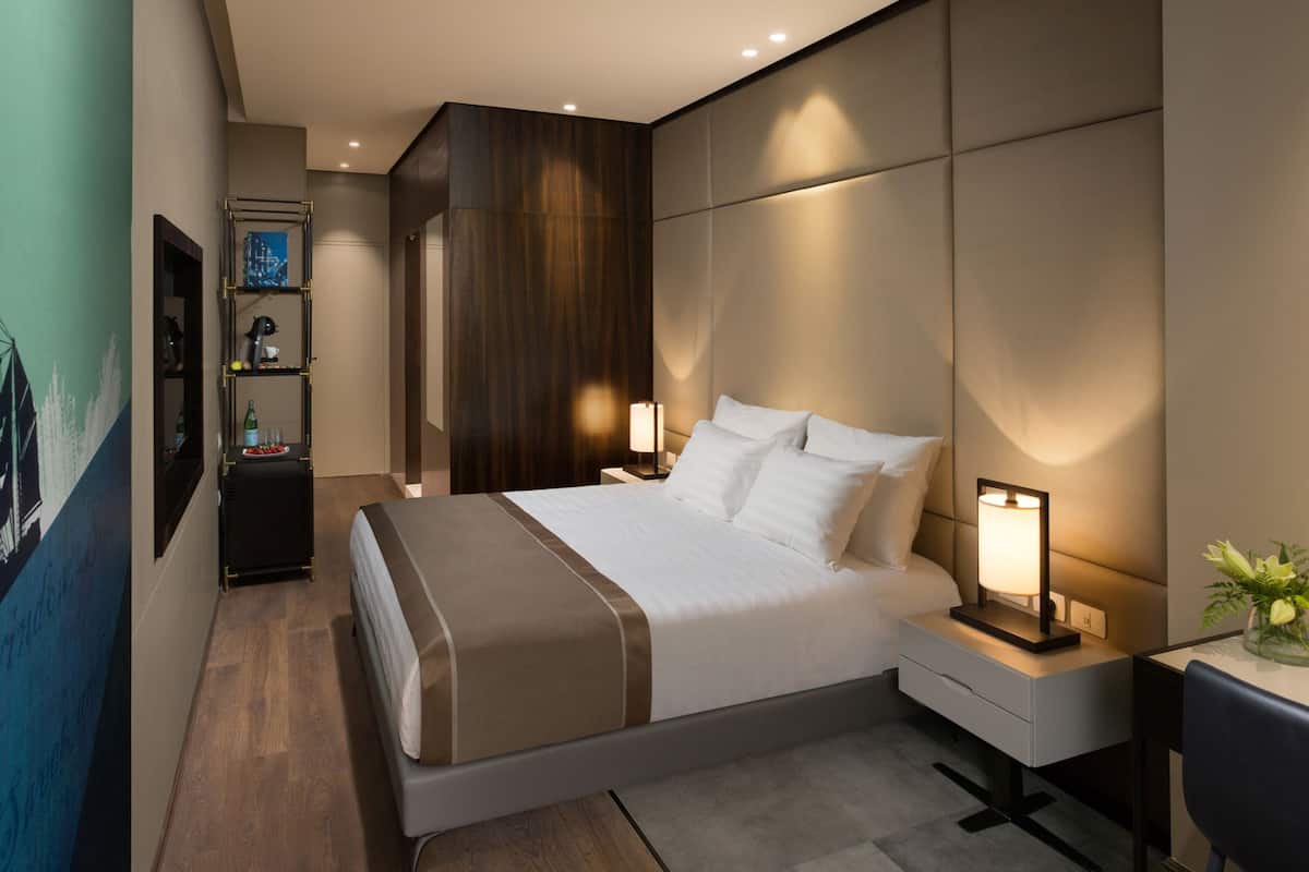 Un dormitorio moderno con una cama grande, mesitas de noche y un estante fijado a la pared.
