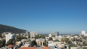 A cityscape with a mix of modern and traditional buildings, a clear sky, and a hilly backdrop.