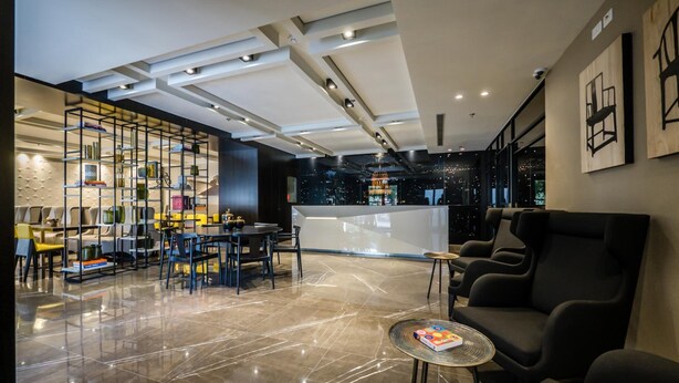 Eine moderne Lobby mit einer Rezeption, einer Sitzecke und einem dekorativen Bücherregal.