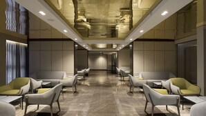 Eine moderne Hotelhalle mit einer zentralen Sitzgruppe, einer hohen Decke mit eingelassener Beleuchtung und einem Marmorboden.