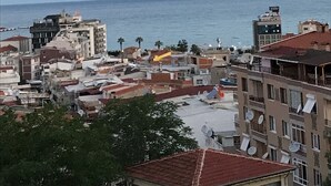 A coastal cityscape with buildings, some with satellite dishes, and a view of the sea. - HBS Hotel (Kusadasi)
