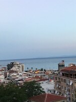 Un paisaje urbano costero con edificios, algunos con antenas parabólicas, y vista al mar.