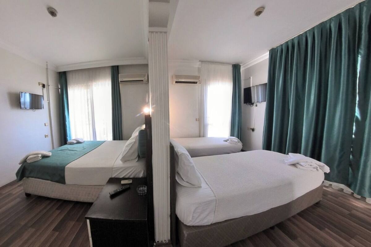 A hotel room with two beds, a flat-screen TV mounted on the wall, and an air conditioning unit.