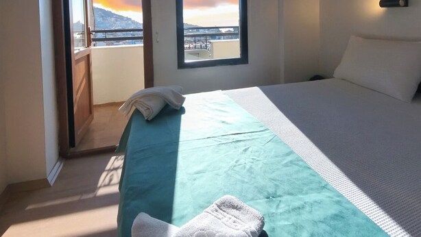 A bedroom with a bed, a window with a view of a sunset, and an air conditioning unit. - HBS Hotel (Kusadasi)
