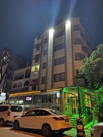Un edificio de varios pisos con un local comercial en la planta baja, fachada de vidrio y señalización iluminada.