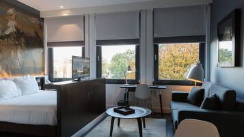 A modern hotel room with a bed, a sofa, a desk, and a chair.