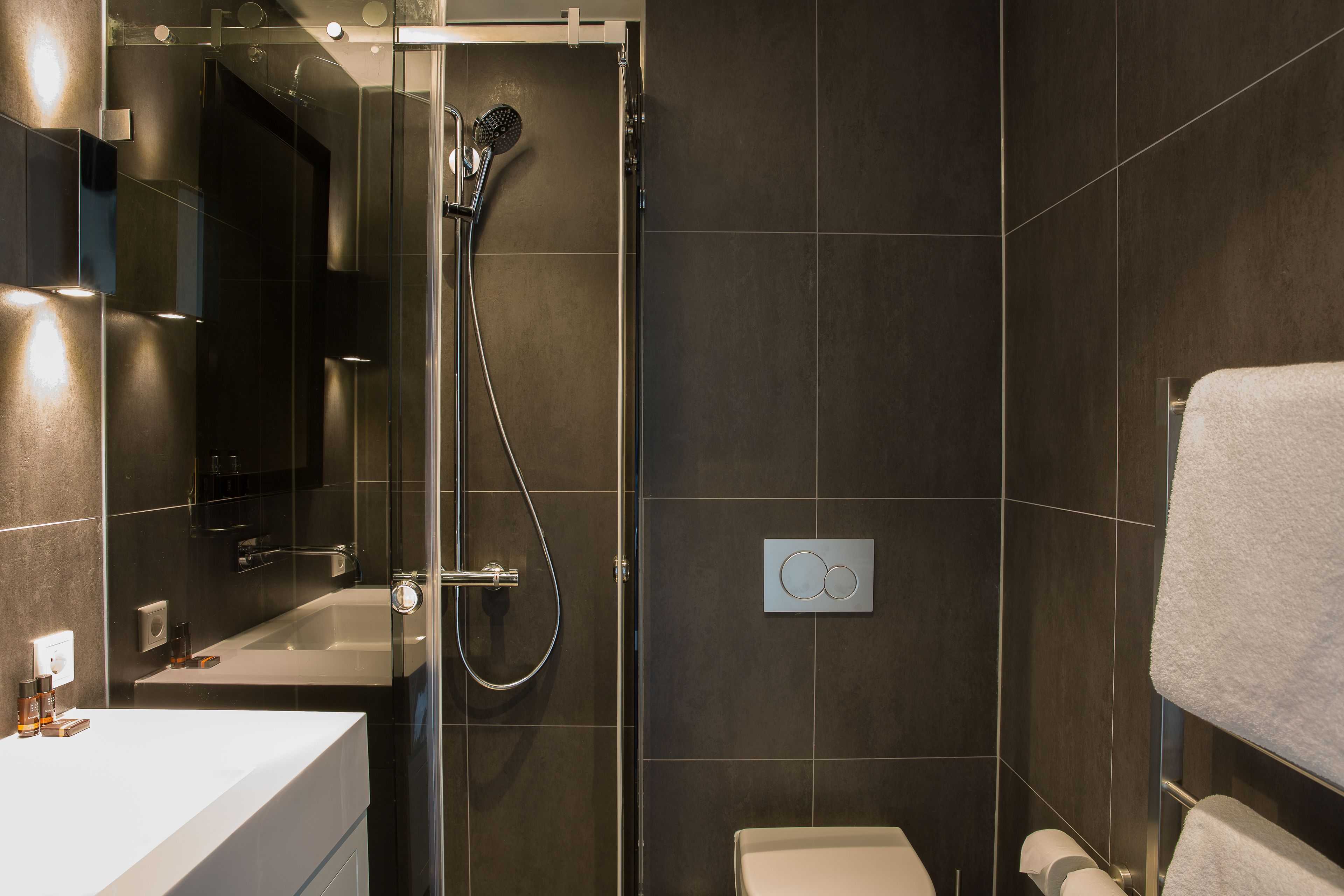 A modern bathroom with a glass-enclosed shower, a standalone bathtub, and a toilet.