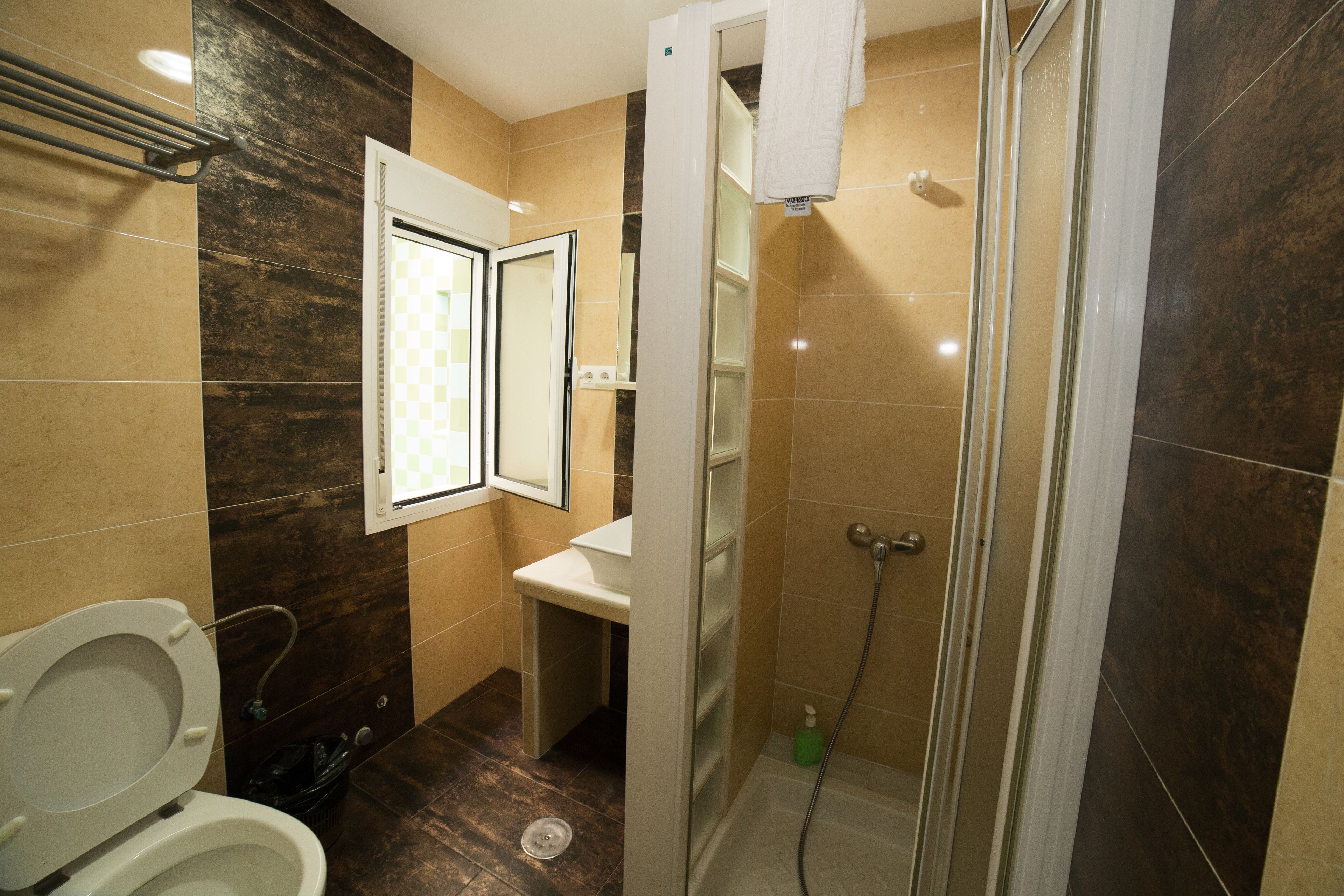 Un baño con inodoro, lavamanos y zona de ducha.