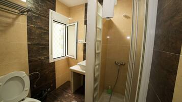 Un baño con inodoro, lavamanos y zona de ducha.