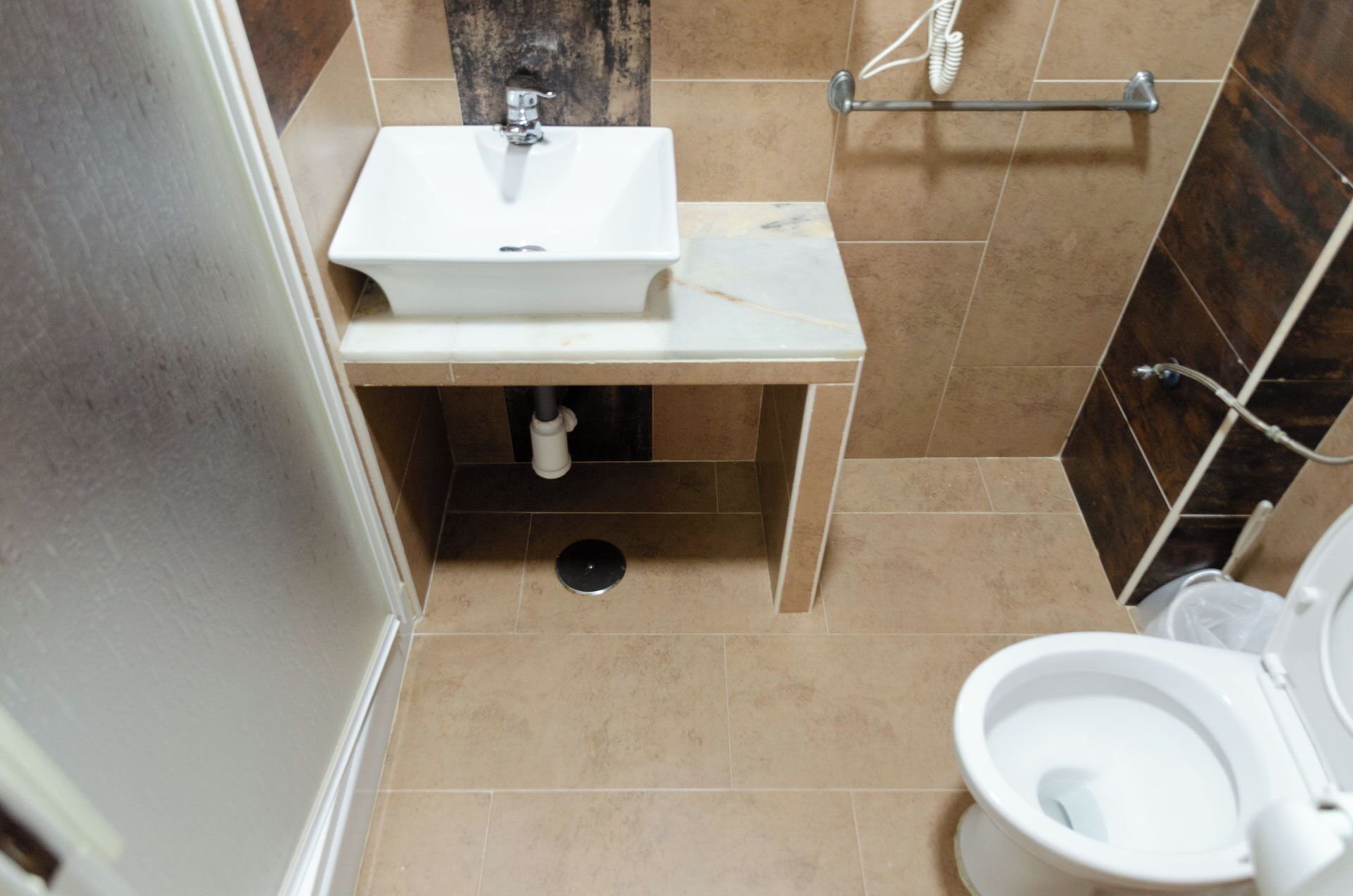 Baño con lavamanos blanco, inodoro y zona de ducha.