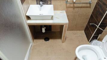 Baño con lavamanos blanco, inodoro y zona de ducha.