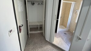 A narrow hallway with a white closet containing a bench and a coat rack. - Hospedaje Lisboa Algeciras (Algeciras)