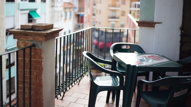 A balcony with a table and chairs, a tiled floor, and a brick wall. - Hospedaje Lisboa Algeciras (Algeciras)