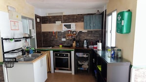 A compact kitchen with a microwave, stove, sink, and a small refrigerator. - Hospedaje Lisboa Algeciras (Algeciras)