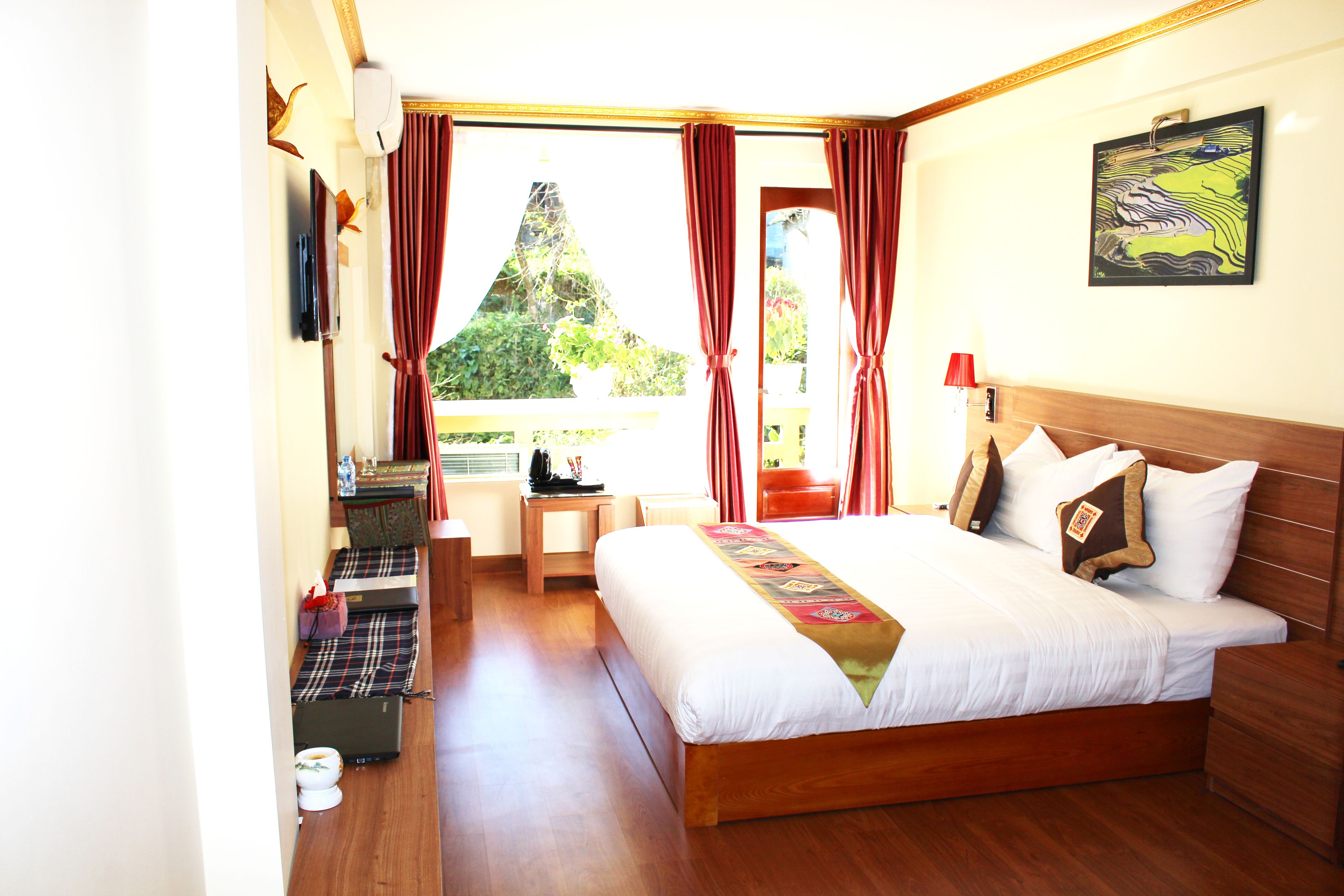 Ein Hotelzimmer mit einem großen Bett, einem Schreibtisch, einem Stuhl und Blick auf Grün.