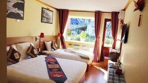 Quarto de hotel com duas camas, varanda e televisão.